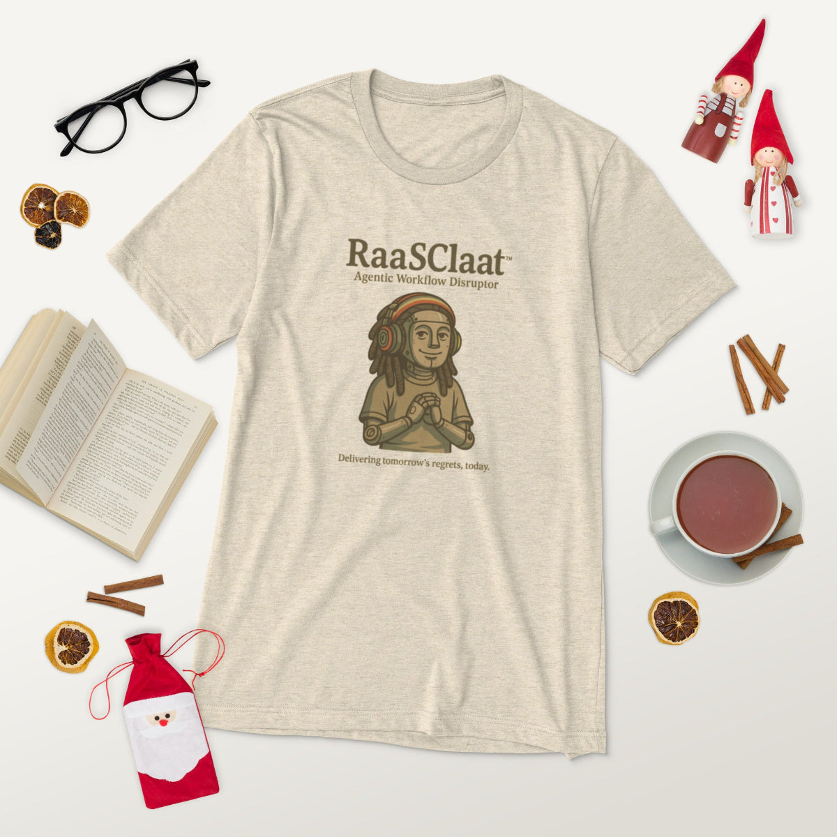 Beige t-shirt with 'RaasClaat' graphic design on a white background with decorative items.